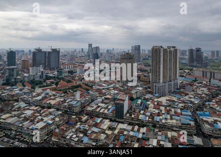 Vista aerea di un vivace skyline urbano con alti edifici e tetti affollati sotto un cielo nuvoloso, Prampi Makara District, Phnom Penh, Cambogia. Foto Stock