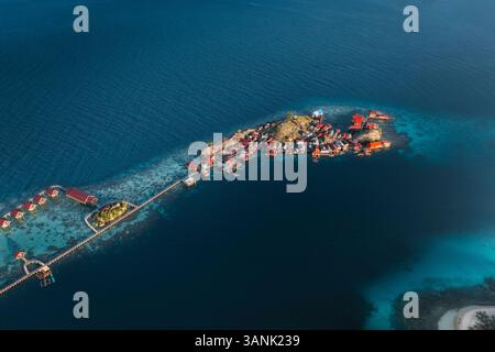 Vista aerea delle serene case sul mare su palafitte collegate da una passerella in un villaggio tropicale, Talatako, Sulawesi centrale, Indonesia. Foto Stock