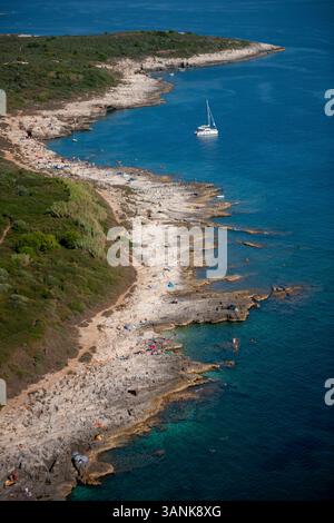 Vista aerea della splendida costa rocciosa con mare tranquillo e barca a vela, Pola, Istria, Croazia. Foto Stock