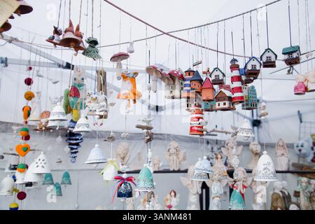 Elementi decorativi e souvenir in argilla di design a forma di fari, campane, case e angeli, realizzati a mano, visualizzato in uno stallo del mercato a. Foto Stock