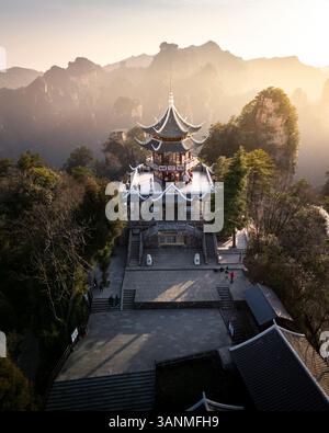 Vista aerea di una pagoda storica e di un tempio circondato da montagne maestose e dalla tranquilla foresta, Zhangjiajie, Cina. Foto Stock