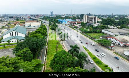 Vista aerea della vivace autostrada circondata da palme ed edifici moderni, Port Harcourt, Nigeria. Foto Stock