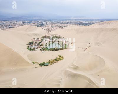 Vista aerea dell'oasi desertica di Huacachina, della città e delle montagne, Perù. Foto Stock