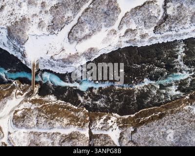 Vista aerea delle acque blu glaciali della cascata di Brúarfoss, circondata dalla foresta e dalla neve in Islanda. Foto Stock