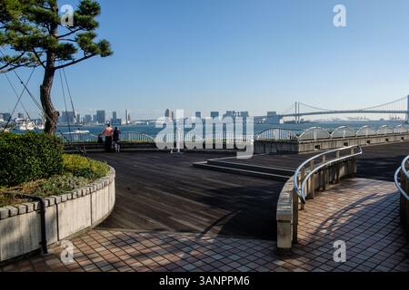 Al Molo di Takeshiba sul lungomare di Tokyo, due persone si trovano sulla passerella che si affaccia sul Ponte dell'Arcobaleno Foto Stock