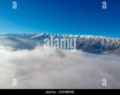 Vista aerea delle montagne di Piatra Craiului dall'alto delle nuvole del parco nazionale di Piatra Craiului, Brasov, Romania Foto Stock