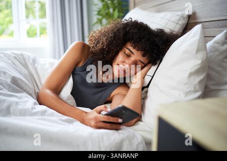 Mattina rilassata a letto con uno smartphone Foto Stock