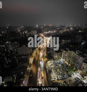 Veduta aerea del vivace paesaggio urbano di notte con edifici illuminati e traffico vivace, Gendaria, Dacca, Bangladesh. Foto Stock