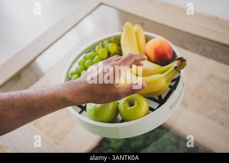 Vista in prima persona ritratto ritagliato di un giovane uomo braccetto di frutta indossa t-shirt interni moderni verdi piatti interni Foto Stock