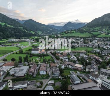 Vista aerea della pittoresca cittadina residenziale circondata da splendide montagne e dalla verde valle al tramonto, Sterzing, Italia. Foto Stock