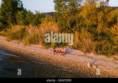Vista aerea due persone che suonano la chitarra sulla spiaggia lungo la costa di Igoumenitsa al tramonto, Epiro, Grecia. Foto Stock
