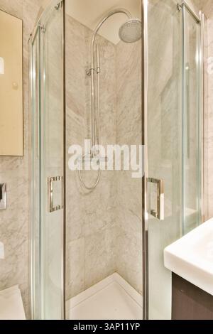 Un box doccia elegante e moderno dalle linee pulite, pareti in marmo e finiture eleganti aggiungono eleganza a qualsiasi spazio in bagno. Foto Stock