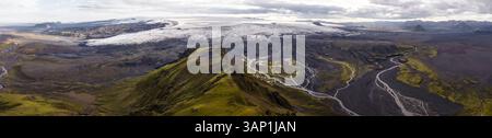 Vista aerea panoramica di un ghiacciaio sulla cima della montagna con fiumi attraverso la valle negli altopiani, Kirkjubaejarklaustur, regione meridionale, Islanda. Foto Stock