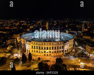 Vista aerea dell'arena storica illuminata e del paesaggio urbano di notte, Pola, Istria, Croazia. Foto Stock
