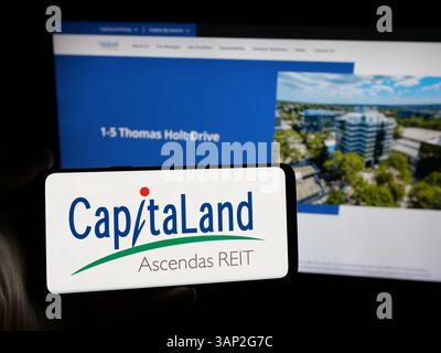 Stoccarda, Germania - 12-04-2024: Persona che detiene lo smartphone con logo della società CapitaLand Integrated Commercial Trust (CICT) sullo schermo Foto Stock