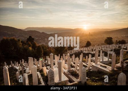 Vista aerea di un tranquillo cimitero con lapidi al tramonto circondato da montagne e paesaggi urbani, Stari Grad, Sarajevo, Bosnia ed Erzegovina. Foto Stock