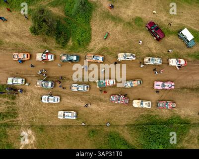 Vista aerea di veicoli fuoristrada che corrono su una strada sterrata circondata da prati panoramici e persone in un evento all'aperto, Mbirikani, Kenya. Foto Stock