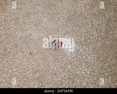 Veduta aerea di una donna che raccoglie acqua dalla terra incrinata in un villaggio costiero colpito dalla siccità, Khulna, Bangladesh. Foto Stock