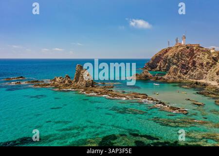 Vista aerea della formazione geologica di rocce vulcaniche nella costa di Cabo de Gata con persone che nuotano nell'Arrecife de las Sirenas e nel faro Foto Stock