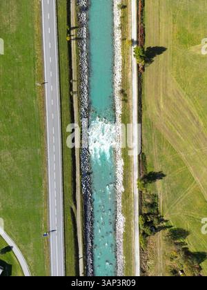 Vista aerea del tranquillo fiume che si snoda attraverso la vegetazione lussureggiante e la tranquilla campagna di Zuoz, Svizzera. Foto Stock