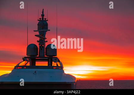 Trasporto di grandi yacht a motore attraverso l'oceano al tramonto con un cielo rosso. Foto Stock