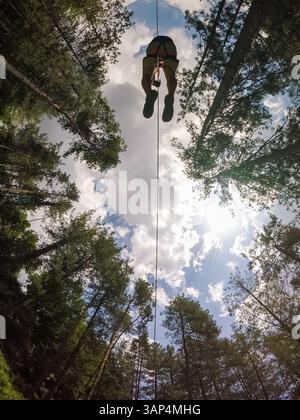 Vista aerea di una persona che attraversa la foresta attraverso un grande cavo zipline. Foto Stock