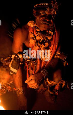 Ritratto di un uomo accanto al fuoco sacro, vestito con un costume rituale durante una cerimonia Bwiti. Foto Stock