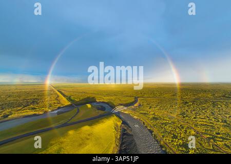 Vista aerea dell'arcobaleno sul verde paesaggio con strada, fiume e ponte, Islanda meridionale Foto Stock