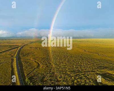 Vista aerea dell'arcobaleno sul verde paesaggio con la circonvallazione, Islanda meridionale. Foto Stock