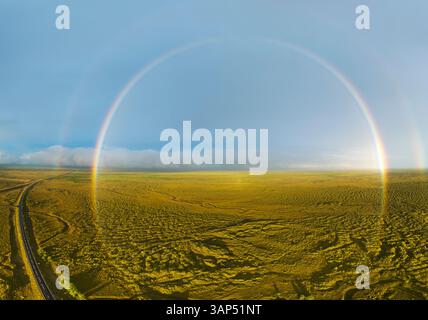 Vista aerea dell'arcobaleno sul verde paesaggio con la circonvallazione, Islanda meridionale. Foto Stock