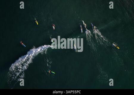 Vista aerea delle persone su tavole da paddle che navigano su onde dinamiche nello splendido oceano di Mandurah, Australia. Foto Stock
