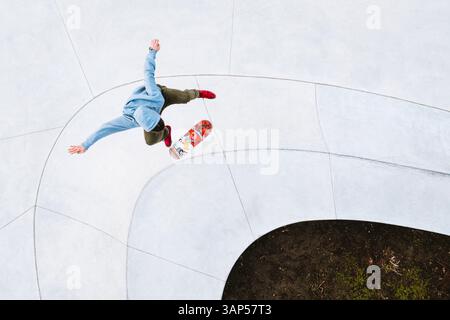 Kaunas, Lituania - 3 aprile 2021: Veduta aerea dello skateboarder professionista che salta e fa il kick flip trick nel parco di pattinaggio urbano di Kaunas, Lituania Foto Stock