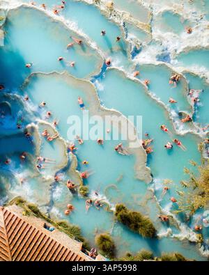 Vista aerea dell'oceano turchese con bagni solari presso le terme di Saturnia, Cascate del Mulino, sorgenti termali calde, Manciano, Italia. Foto Stock