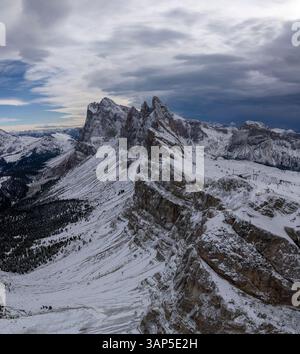 Vista aerea delle maestose montagne innevate e delle aspre scogliere sotto un cielo nuvoloso, Ortisei, Italia. Foto Stock