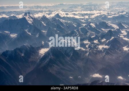 Vista aerea delle maestose cime innevate e delle aspre montagne sotto le nuvole, della catena montuosa dell'Himalaya, Pakistan. Foto Stock