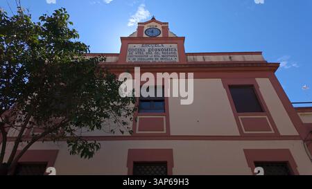 Vista ad angolo basso dell'escuela cocina economica de ntra sra del rosario, facciata con torre dell'orologio a Siviglia, Spagna Foto Stock