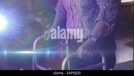 Immagine di una luce che si muove sulla sezione centrale di una donna anziana utilizzando un telaio da passeggio Foto Stock