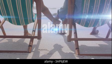 Immagine di una luce che si muove sopra una coppia anziana sulle sdraio che si tengono per mano Foto Stock