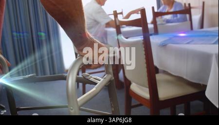 Immagine della luce che si muove sopra un anziano nella sala da pranzo utilizzando una cornice per camminare Foto Stock