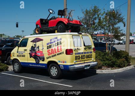Pubblicità colorata su furgoni con golf cart unico sul tetto nel parcheggio. Concetto di marketing creativo con un furgone che mostra un campo da golf in miniatura CA Foto Stock