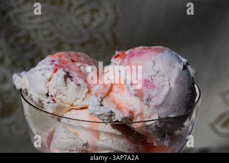 Una ciotola di gelato alle fragole. Il recipiente è pieno a metà e il gelato si sta sciogliendo Foto Stock