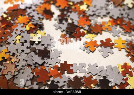 Puzzle rosso, arancione, giallo, marrone e nero sparsi sulla superficie bianca Foto Stock