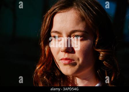 Giovane donna penosa all'aperto, sotto la luce del sole. Foto Stock
