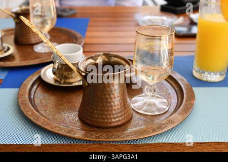 Qahwa. Tradizionale caffè omanita con cardamomo in una cezva di rame servito su un vassoio inseguito con un bicchiere d'acqua e una piccola tazza di caffè Foto Stock