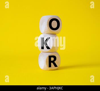 Obiettivi OKR e simbolo dei risultati chiave. Cubi in legno con parole obiettivi OKR e risultati chiave. Bellissimo sfondo giallo. Business e OKR. Foto Stock