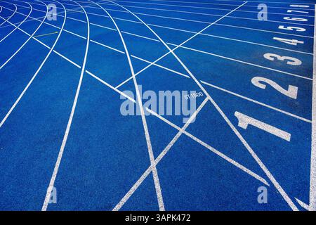 Piste da corsa blu in uno stadio con numeri sulla linea di partenza. Intersezione delle linee di marcatura. Foto di alta qualità Foto Stock