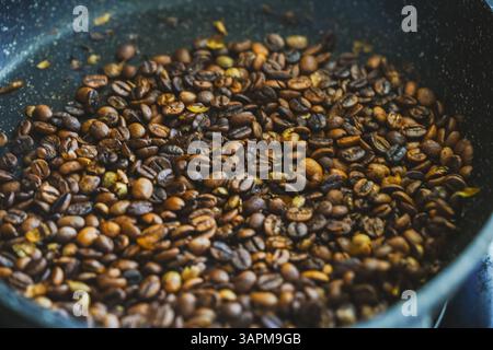 Il processo di tostatura del caffè. I chicchi di caffè vengono tostati in una padella. Primo piano. Sfondo. Foto di alta qualità Foto Stock