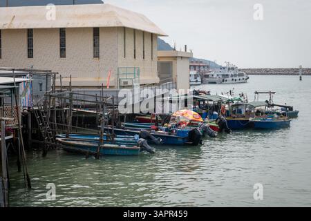 Hong Kong. Cina- 02.27.2025. Piccole barche ormeggiate tra l'ingresso del canale marino e il porto del villaggio di pescatori Tai o, l'isola di Lantau. Foto Stock