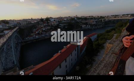 Un momento tranquillo catturato mentre il sole tramonta su Porto, Portogallo. La vista include il ponte Dom Luís i, tetti colorati, il fiume Douro e una pace Foto Stock