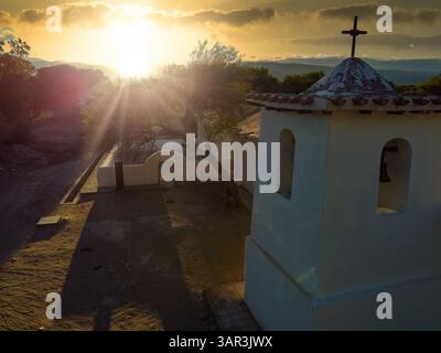 Fotografia del campanile della chiesa di San Pedro a Fiambala, Catamarca, dipinto di bianco e incandescente sullo sfondo di un sereno tramonto andino. A s Foto Stock